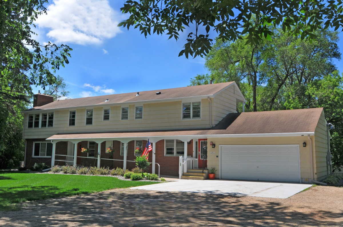 A suburban house with a porch, garage, and front yard on a sunny day.