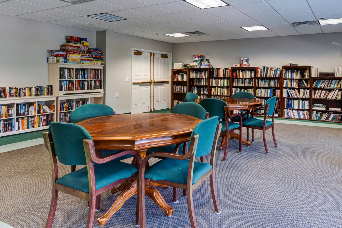 A cozy library with tables and chairs surrounded by bookshelves filled with books.