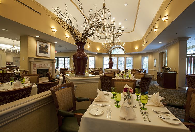 An elegant dining room with beautifully set tables, a chandelier, and decorative vases.