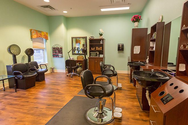 A well-organized hair salon with barber chairs and mirrors on a wooden floor.