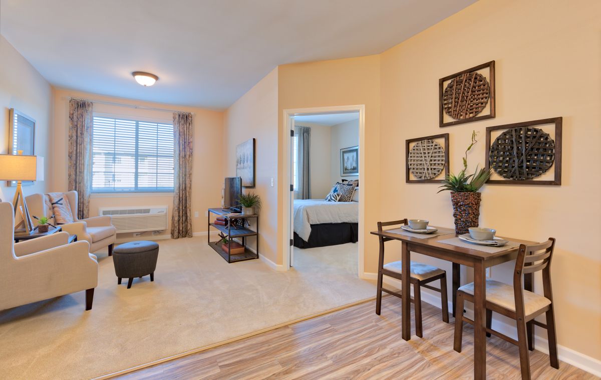 A modern apartment featuring a cozy living room with a view into the bedroom and an adjacent dining area.