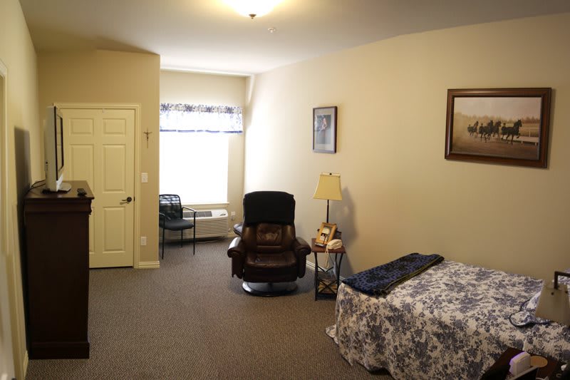 A cozy bedroom with a comfortable chair and a window letting in natural light.