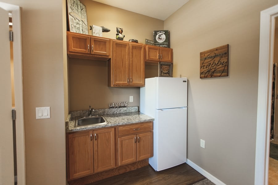 A compact kitchen area featuring wooden cabinets, a refrigerator, and a small sink with a countertop.