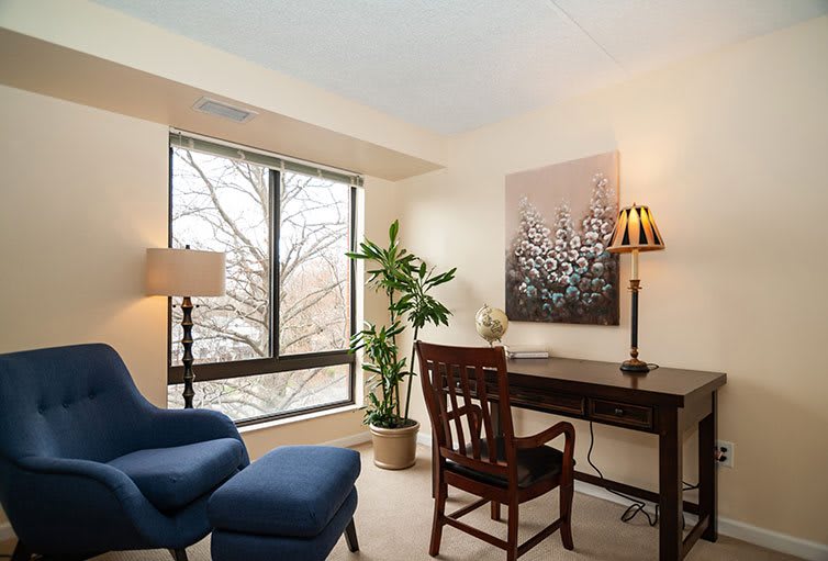 A cozy office space with a wooden desk, comfortable chairs, and a large window providing natural light.