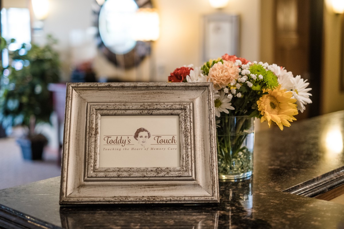 A decorative picture frame on a table next to a bouquet of flowers.
