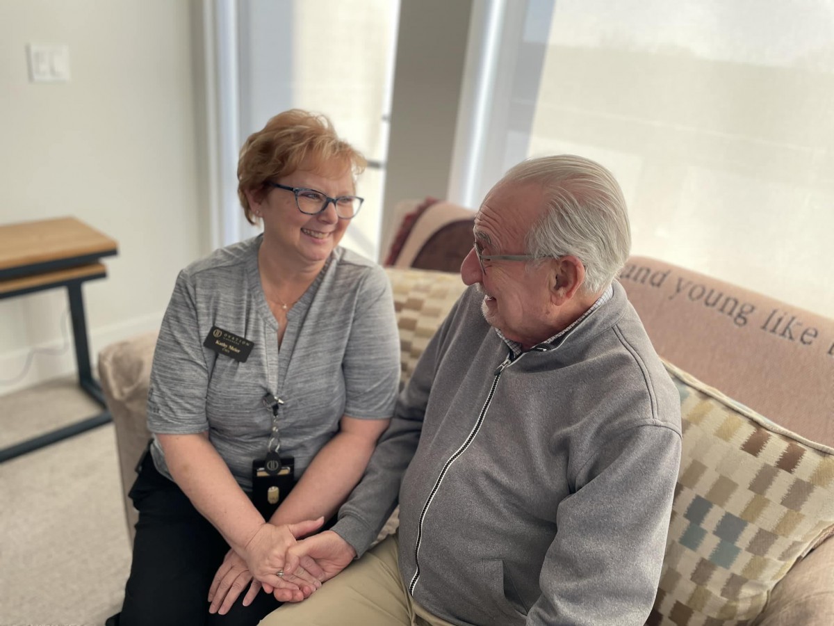 An elderly couple sitting on a sofa, engaged in a pleasant conversation.