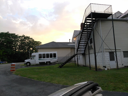 A view of a building with an external staircase and a parked vehicle nearby.