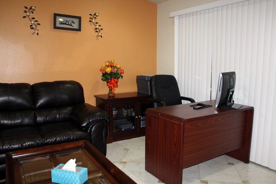 A cozy office space with a desk, chairs, and a leather sofa.