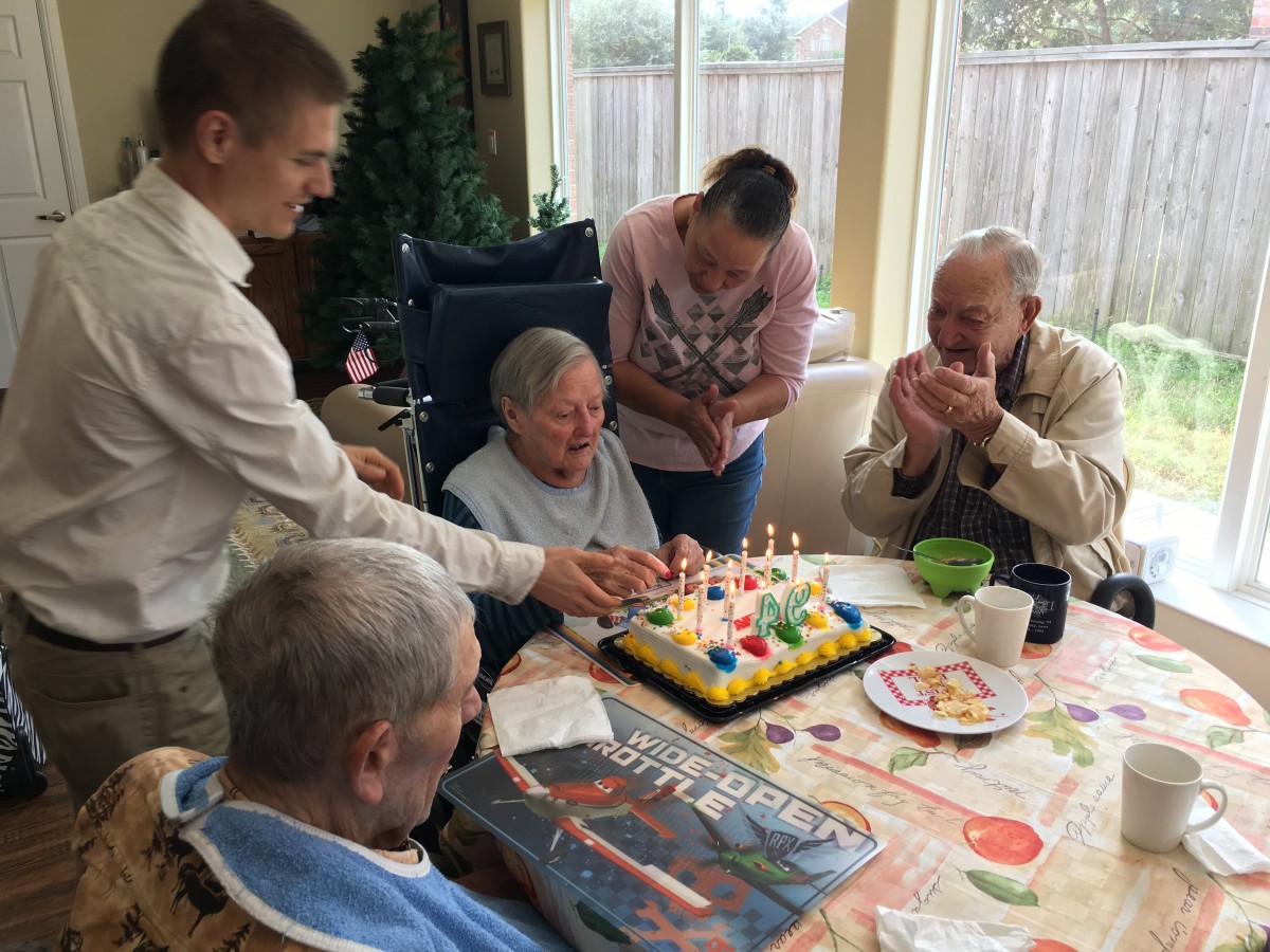 A joyful family gathering celebrating a birthday with a colorful cake and candles.