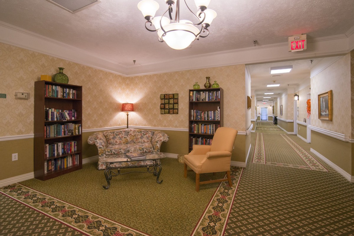 A cozy hallway with bookshelves, a sofa, and an armchair under a chandelier.