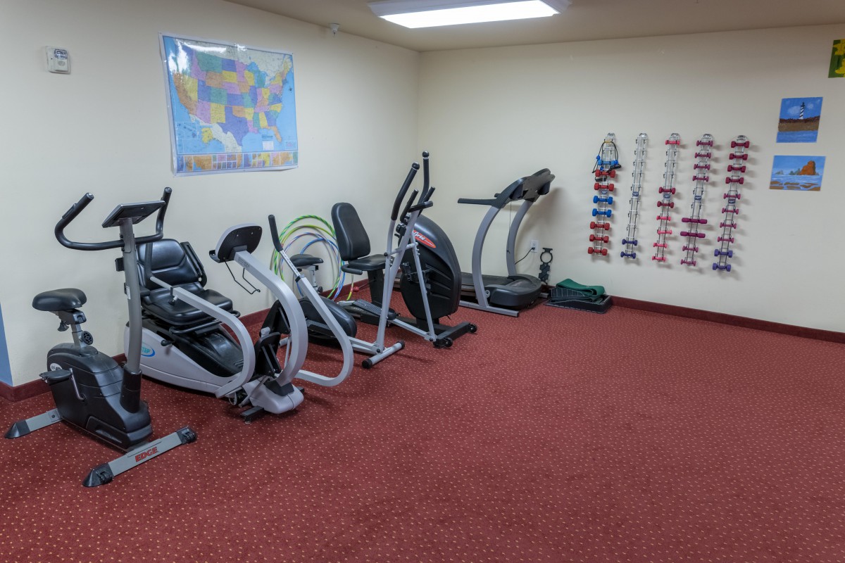 A small gym with exercise equipment including a treadmill and stationary bikes.
