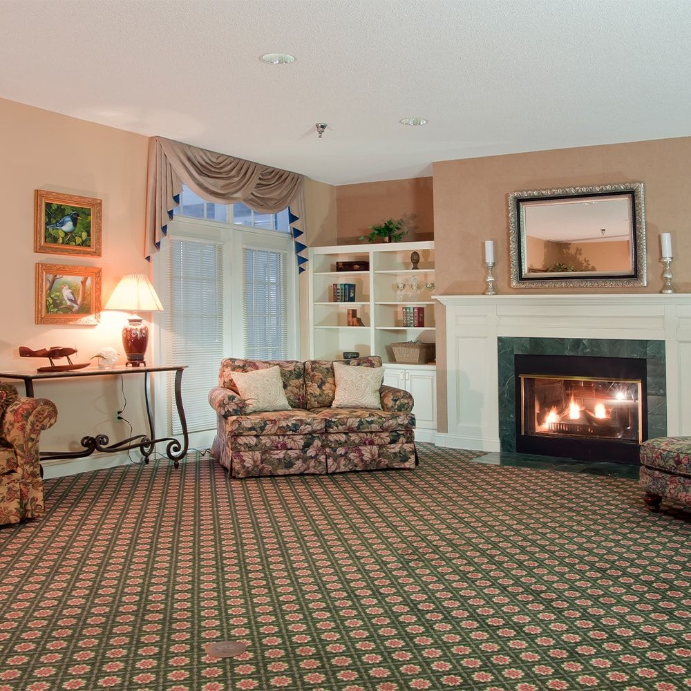 A cozy living room with a fireplace and floral patterned furniture.
