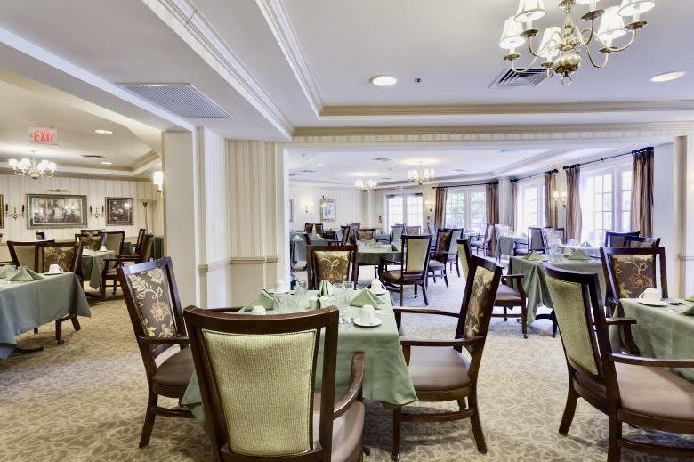 Elegant dining area with neatly arranged tables and chairs, featuring chandeliers.