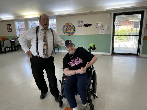 A moment shared between a caregiver and an individual in a wheelchair, showcasing companionship and support.
