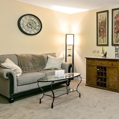 A cozy living room featuring a comfortable sofa, a glass coffee table, elegant wall art, and a floor lamp for ambient lighting.