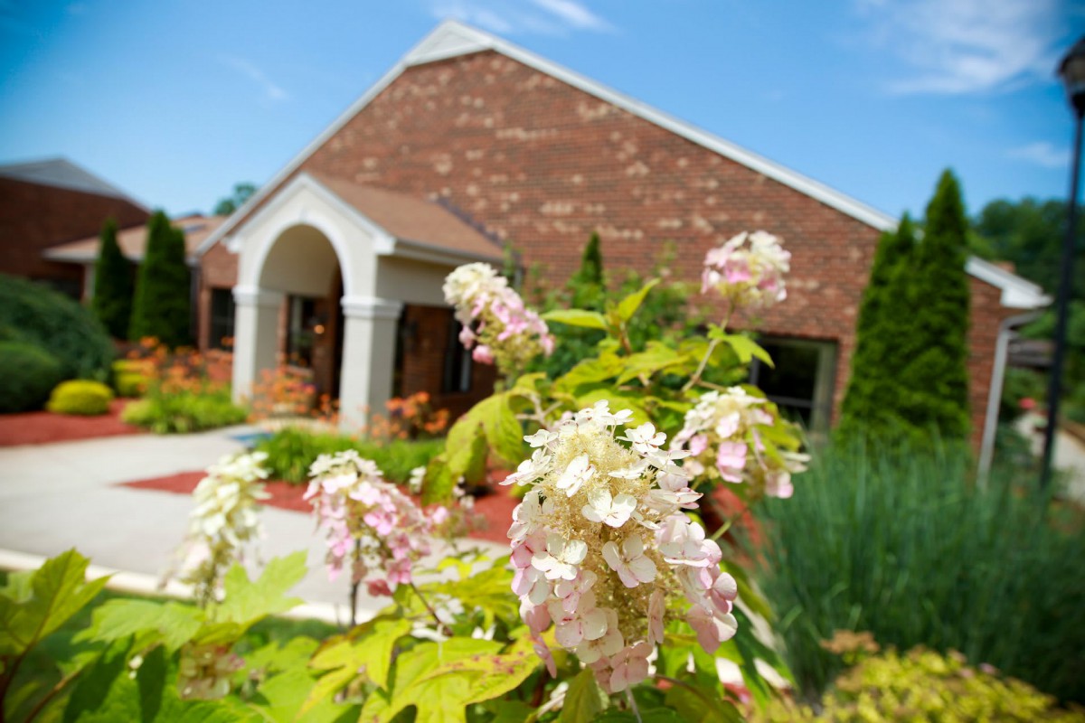A brick building surrounded by a garden with blooming flowers.