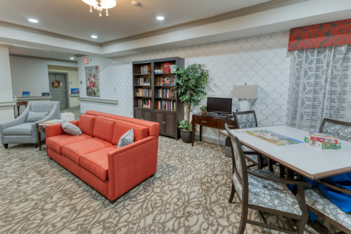 A cozy living room with a red sofa, bookshelf, desk, and decorative elements.