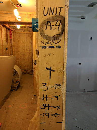 Measurement and marking on a wooden beam in a construction site.