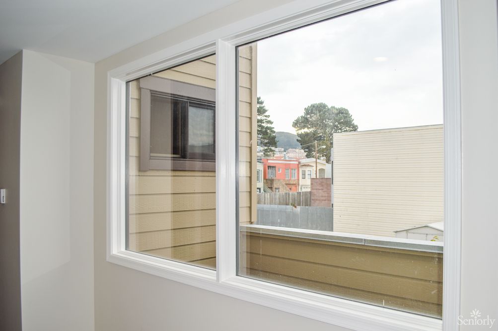 A view from an indoor window overlooking neighboring buildings and trees.