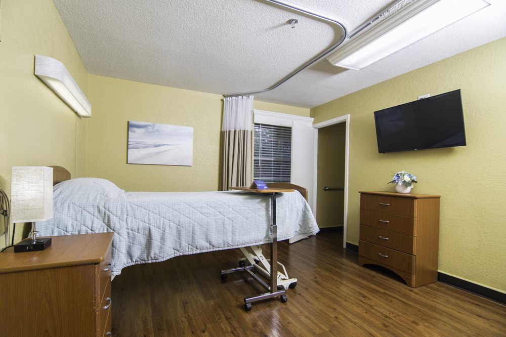A clean and organized hospital room with a bed, television, and essential furniture.
