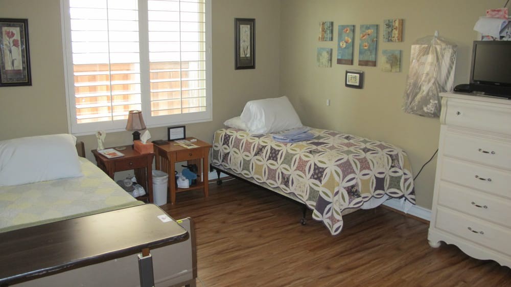 A cozy bedroom featuring a single bed with patterned bedding, wooden flooring, and wall decorations.