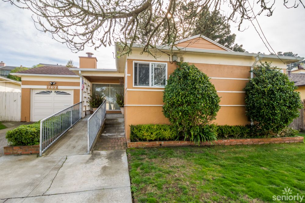 A suburban house with a neatly trimmed lawn and driveway leading to the back.