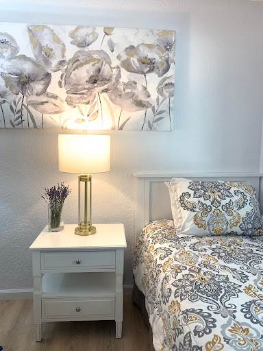 A cozy and well-decorated bedroom featuring a stylish nightstand, decorative lamp, and patterned bedding.