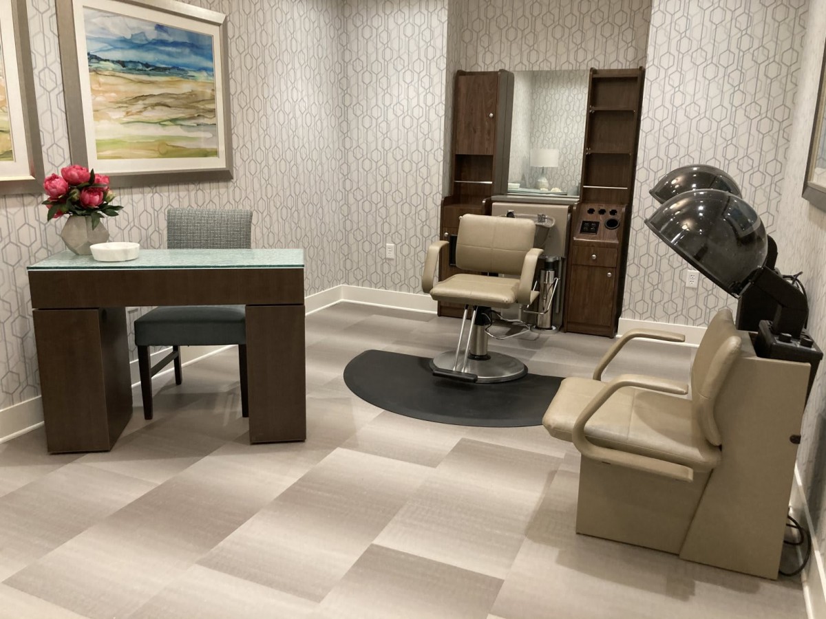 A modern salon interior with stylish chairs, a hairdryer, and a sleek desk.