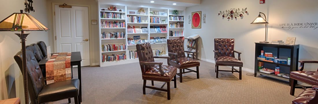 Cozy library reading area with bookshelves and chairs.