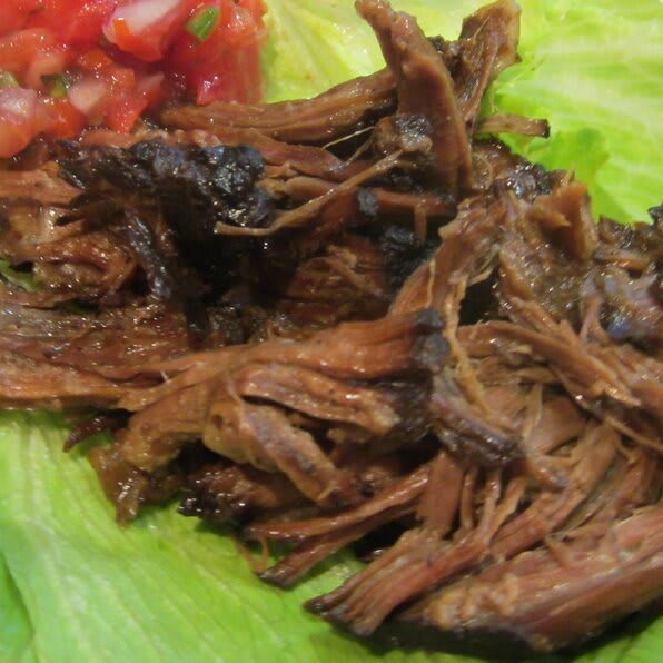 Shredded beef served on lettuce with a side of salsa.