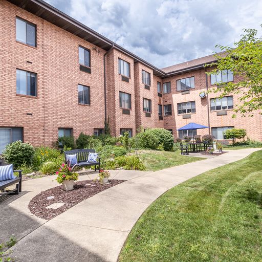 A brick apartment building with a landscaped garden and pathway.