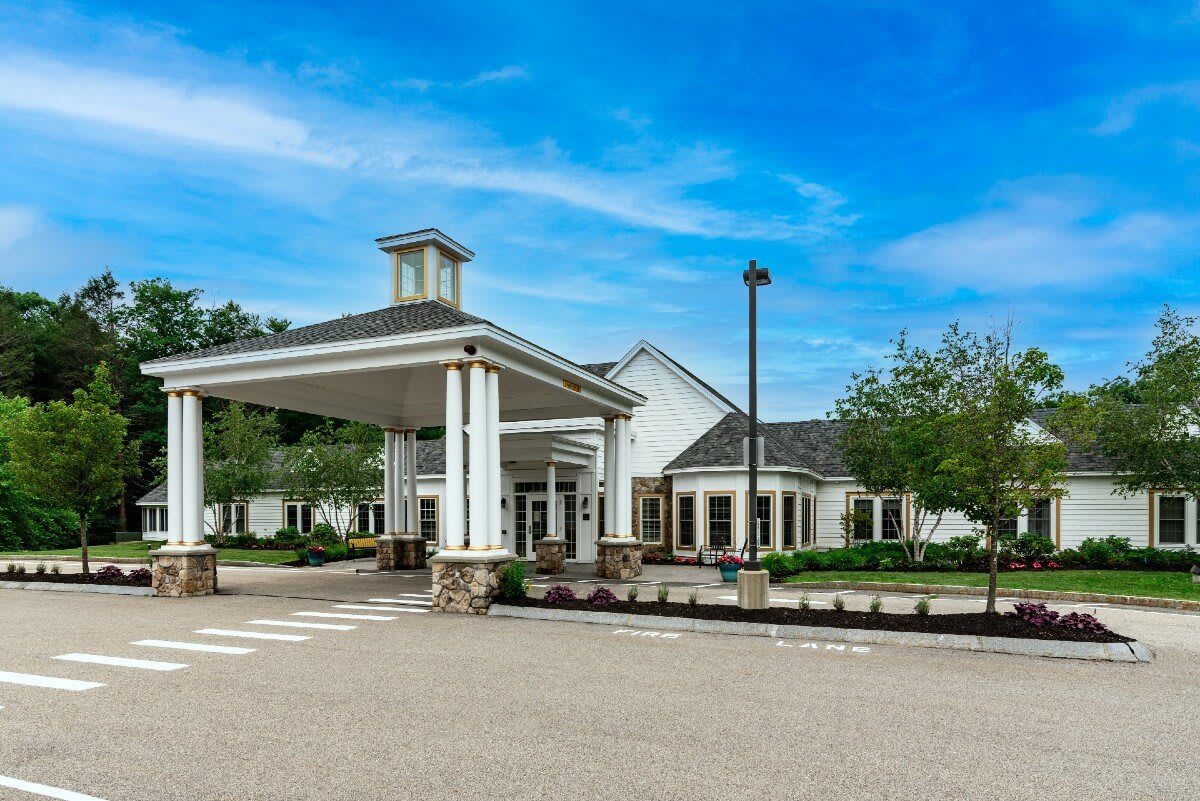 A modern building exterior with a covered entrance and surrounding greenery.