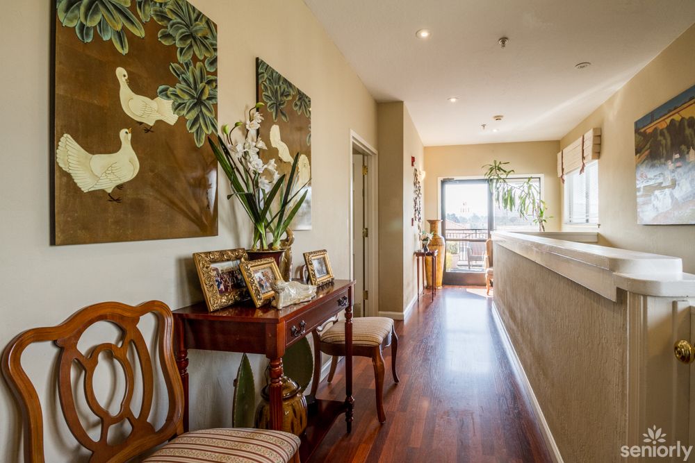 A warmly decorated hallway with wooden flooring, adorned with artwork and family photos.