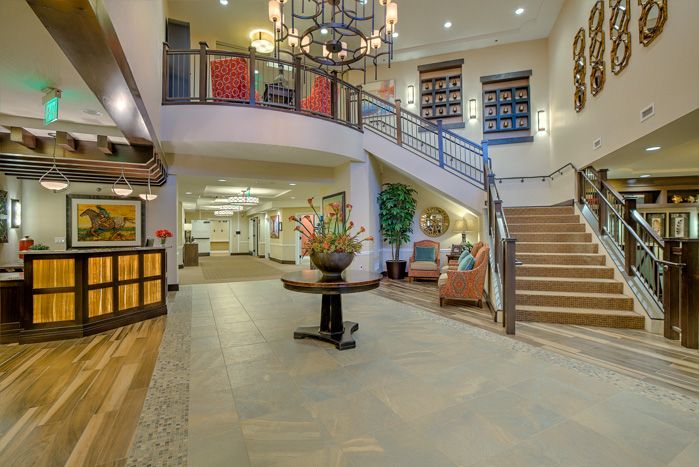 Spacious hotel lobby with a grand chandelier and elegant staircase.