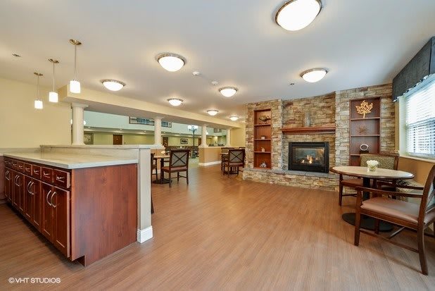 A cozy lounge area featuring a stone fireplace, wooden floors, and multiple seating arrangements.