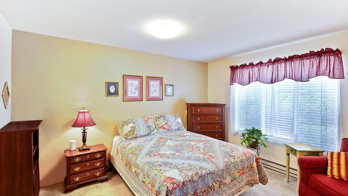 A cozy bedroom with a neatly made bed, dresser, and decorative artwork on the walls.