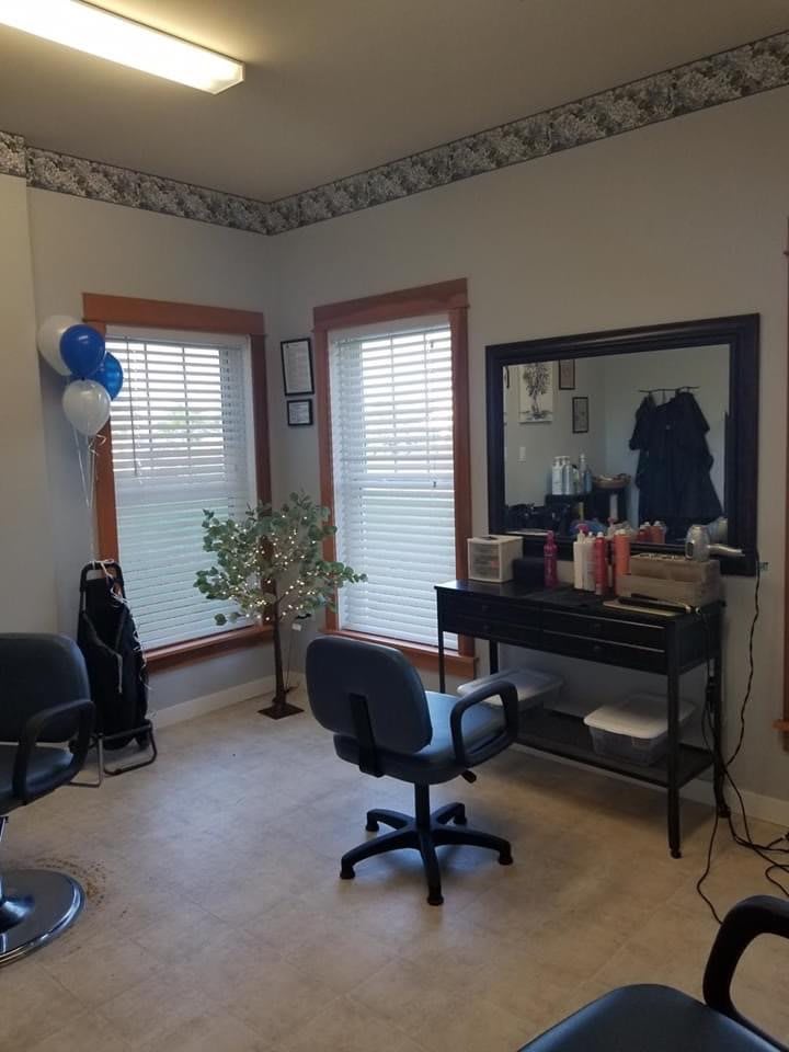 A cozy hair salon interior with chairs and a large mirror.