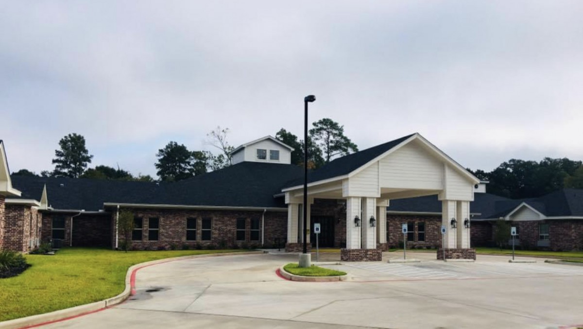 A building with a covered entrance and driveway on an overcast day.