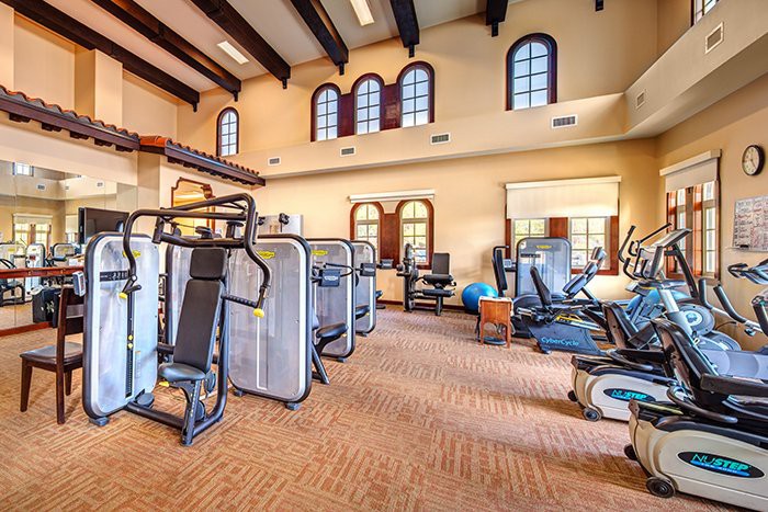A well-equipped gym with various exercise machines and a spacious interior.