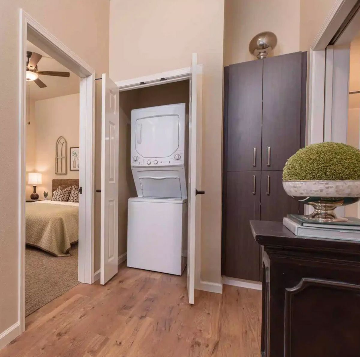 A cozy home interior with a compact laundry area featuring a stacked washer and dryer, adjacent to a bedroom.