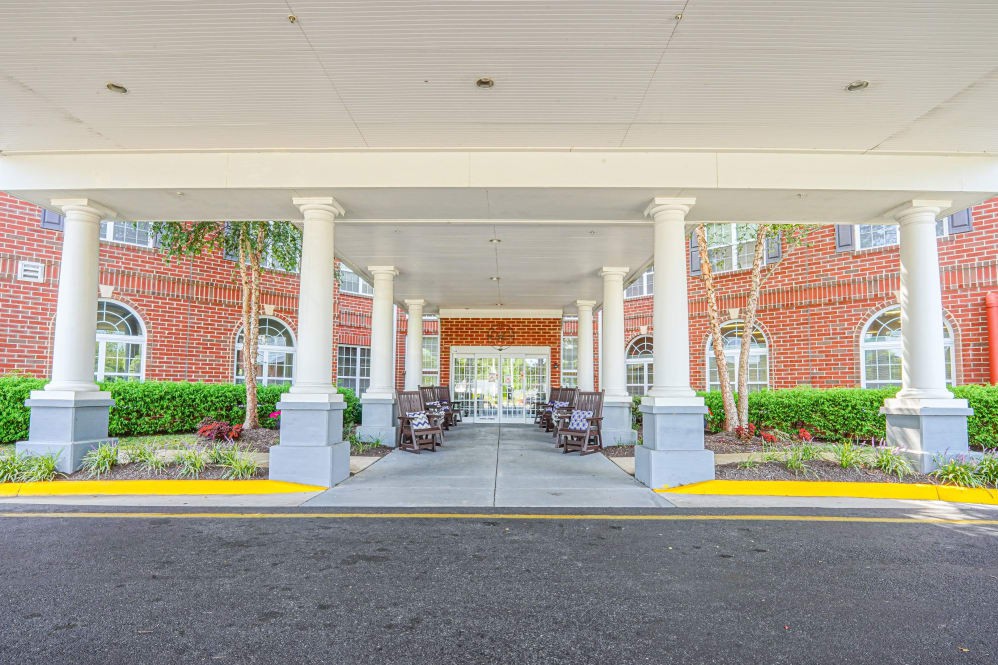 A covered entrance to a building with columns and surrounding greenery.