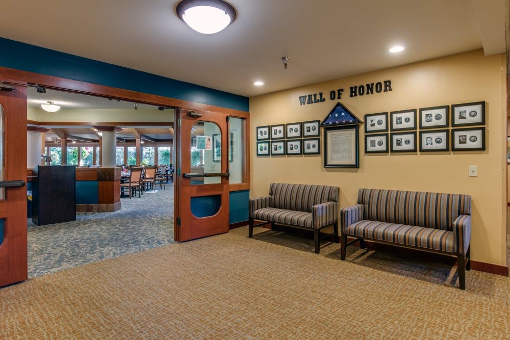 A hallway with a 'Wall of Honor' displaying framed photographs, accompanied by a seating area.