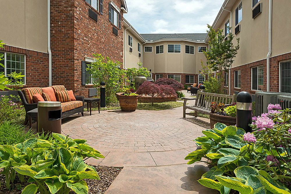 A peaceful courtyard with benches, plants, and a paved walkway between residential buildings.