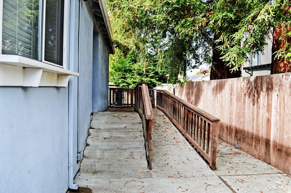 An outdoor accessibility ramp alongside a building, leading to an entrance.