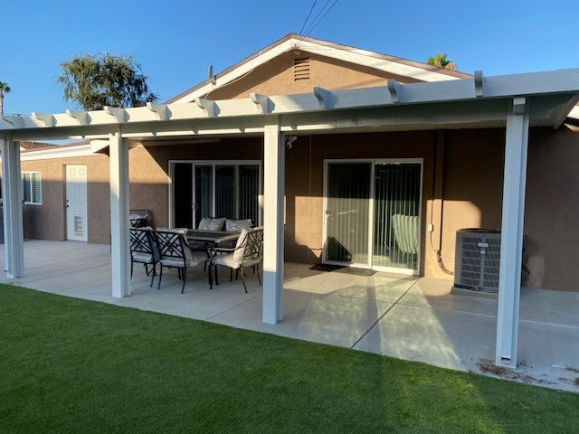 A backyard patio with outdoor furniture and a neatly maintained lawn.