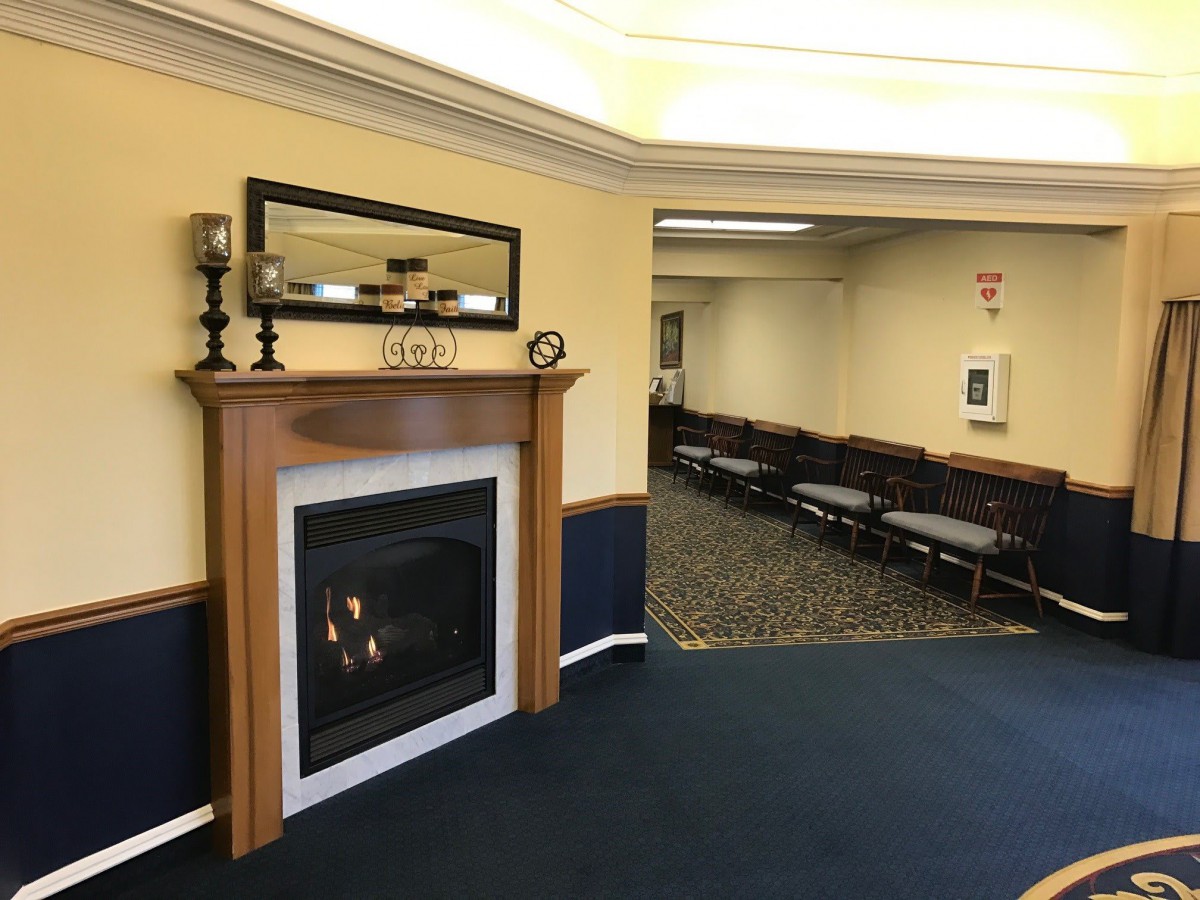 A cozy interior featuring a fireplace and a mirror, adjacent to a meeting room with chairs lined up.