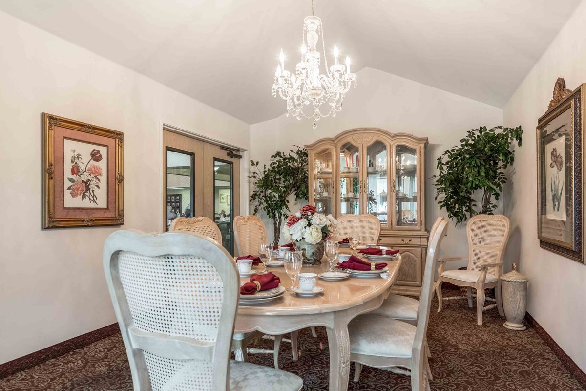 An elegant dining room with a chandelier, featuring a beautifully set table and classic furniture.