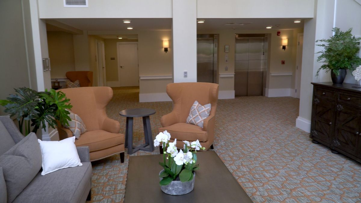 A cozy lobby area with comfortable chairs, a small table, and elevators in the background.