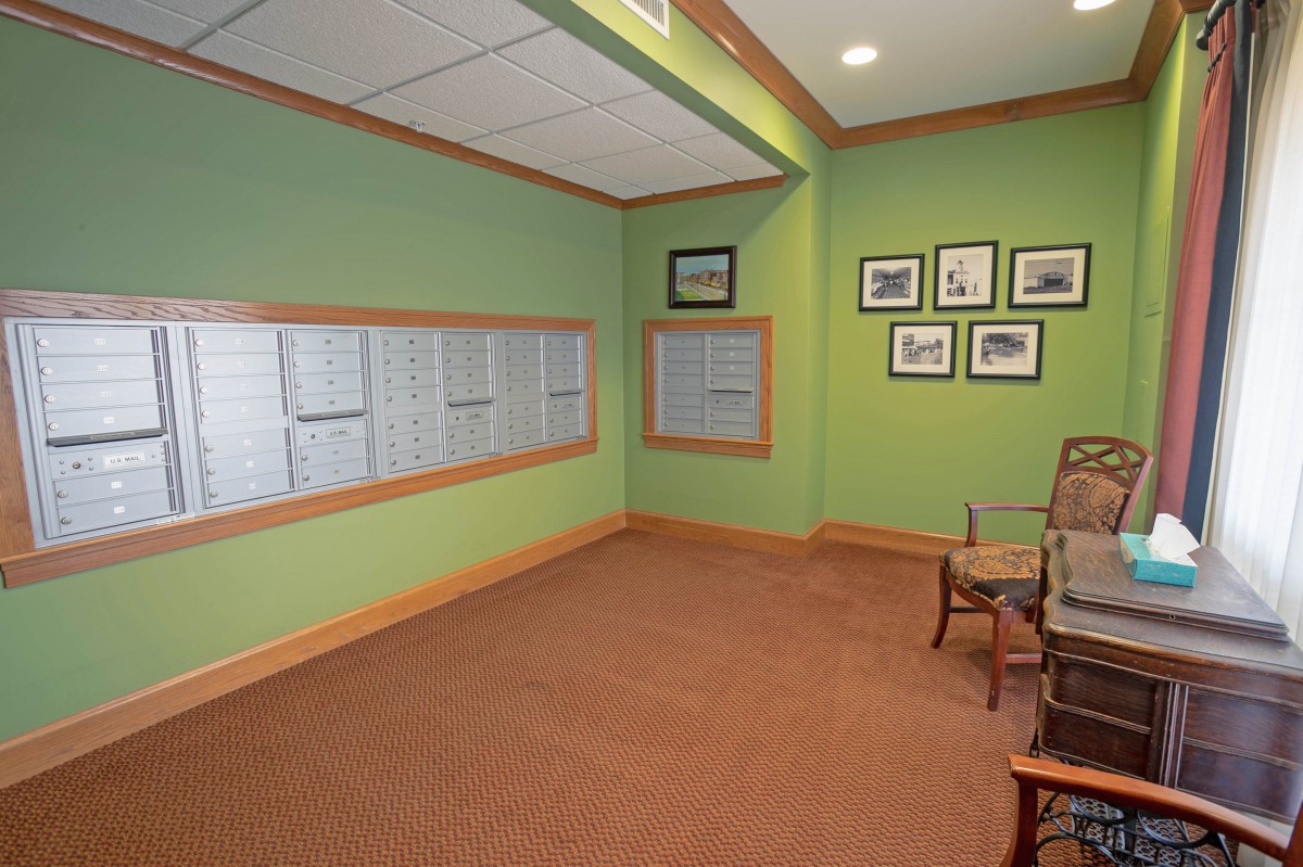 A small waiting area with green walls, several chairs, and framed pictures on the wall.