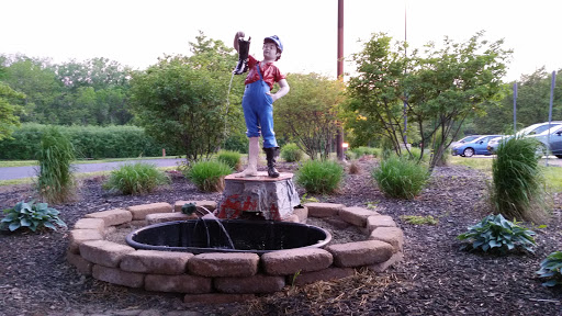 A charming garden fountain featuring a statue of a boy holding a bucket, surrounded by lush greenery.